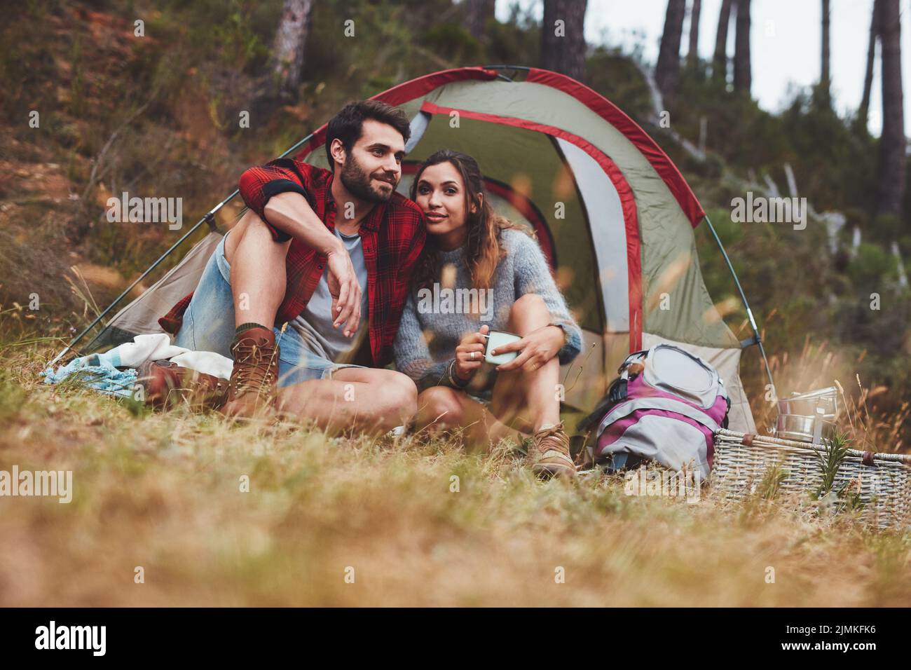 Liebevolles junges Paar auf einem Campingurlaub. Das Paar sitzt zusammen vor ihrem Zelt. Stockfoto