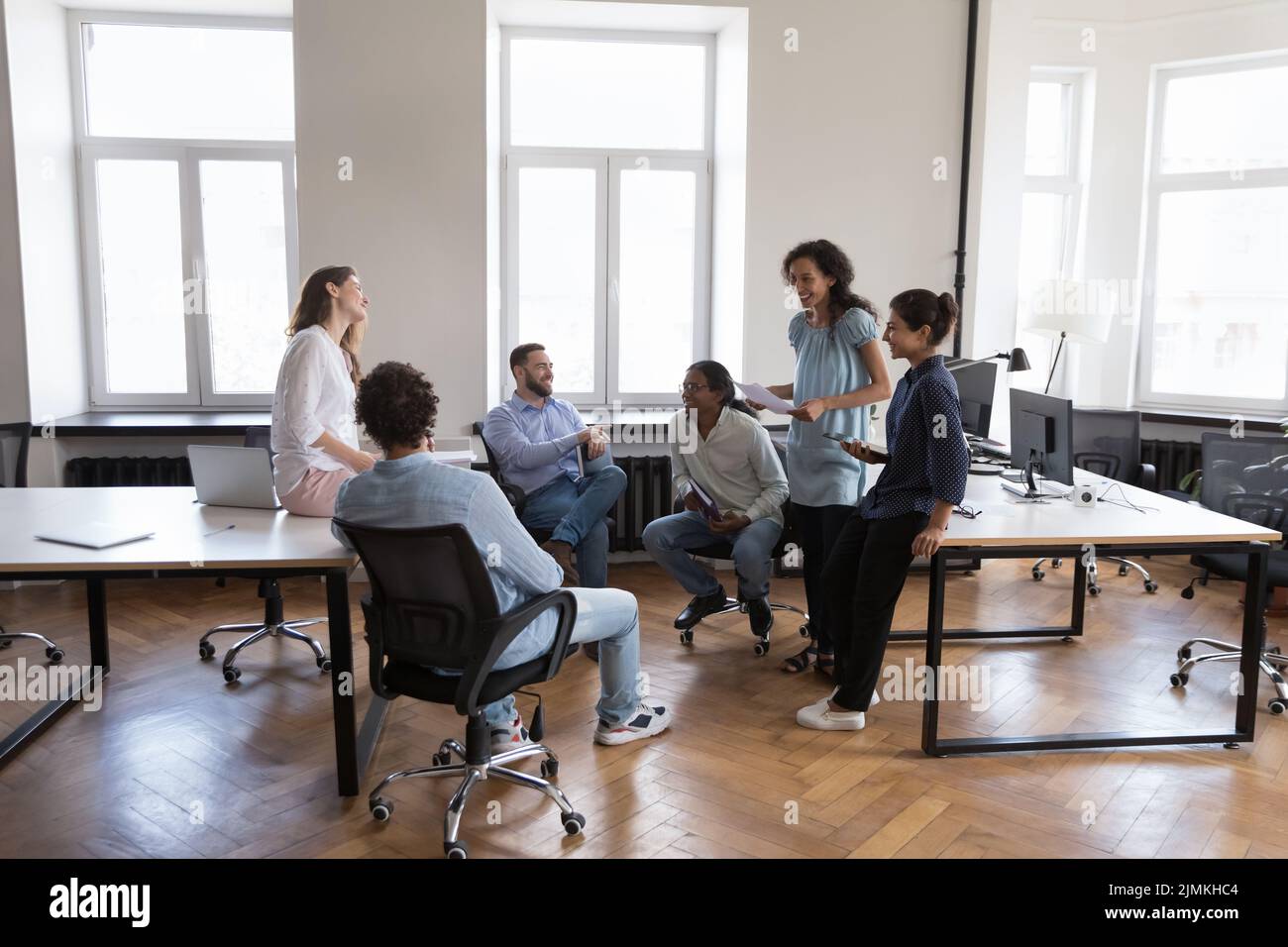Sechs freundliche, multiethnische Büromitarbeiter sprechen während eines Gruppenmeetens Stockfoto