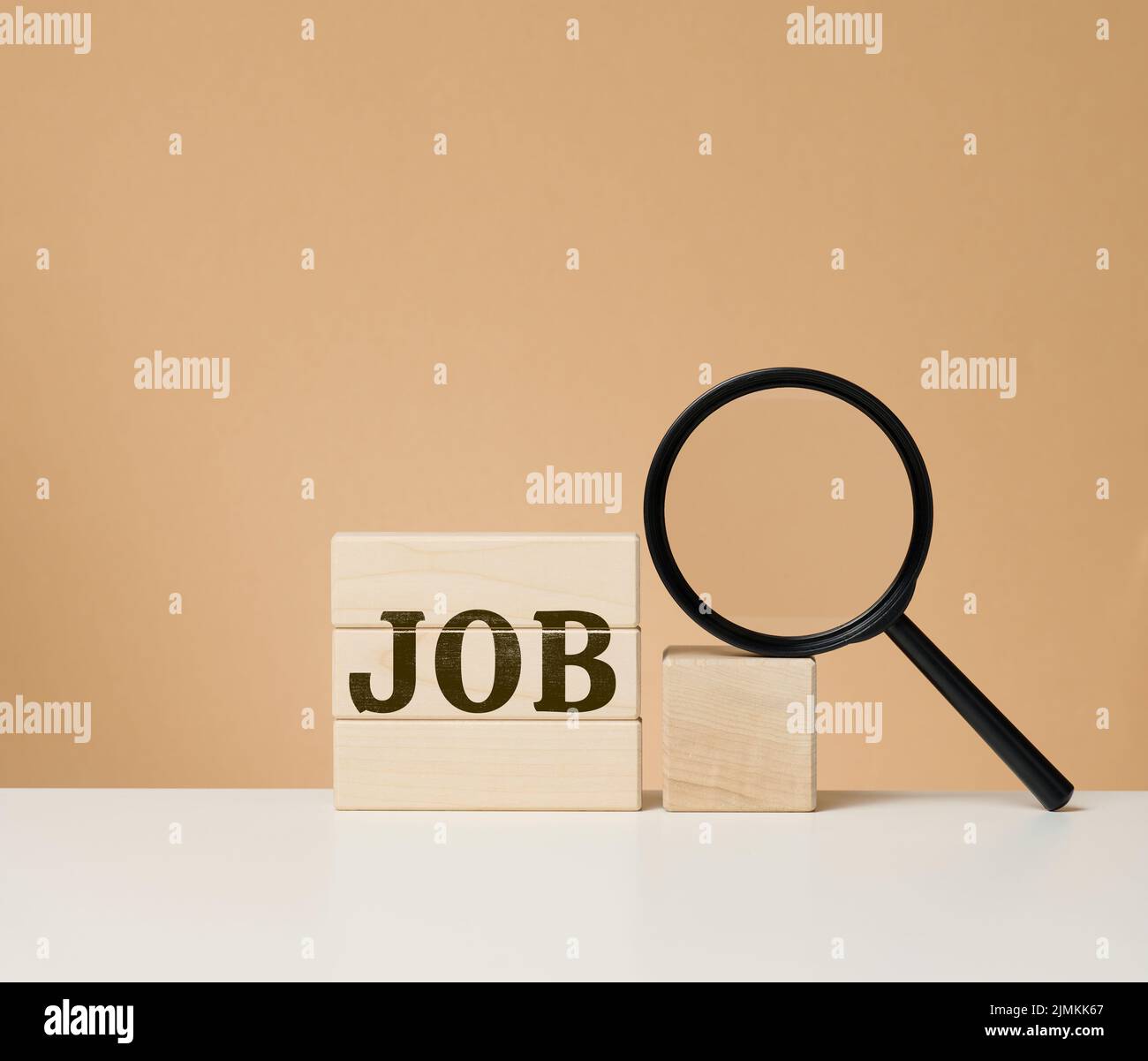 Holzwürfel mit der Aufschrift und einer schwarzen Lupe auf einem weißen Tisch. Jobsuche, Arbeitslosigkeit Stockfoto