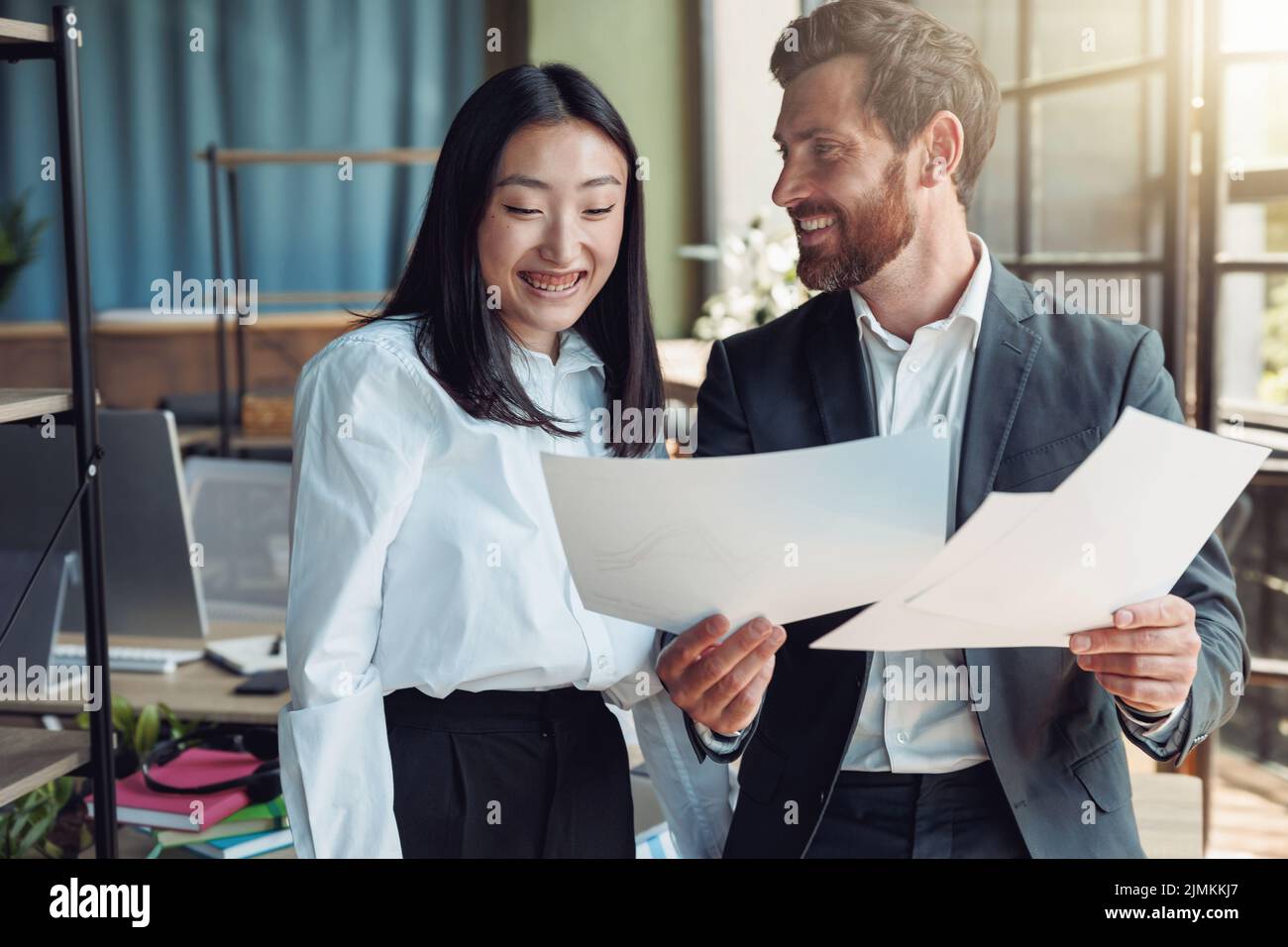 Zwei Kollegen schauen sich Dokumente an und lächeln im Büro Stockfoto