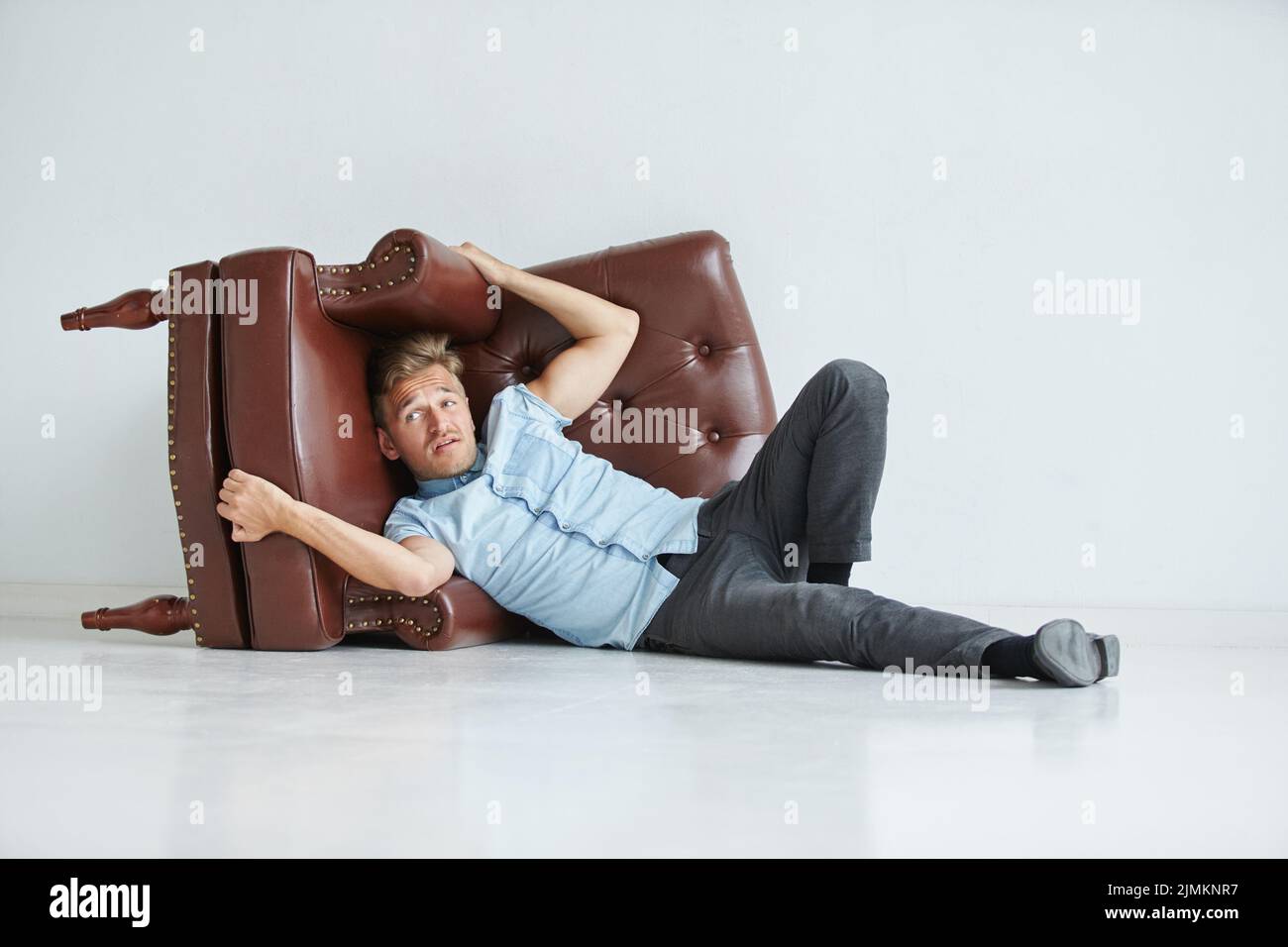 Brutaler Mann in einem Hemd mit kurzen Ärmeln, der auf dem Stuhl sitzt, seine Fäuste geballt, leicht gebeugt, unter dem Blick der Stirn Stockfoto