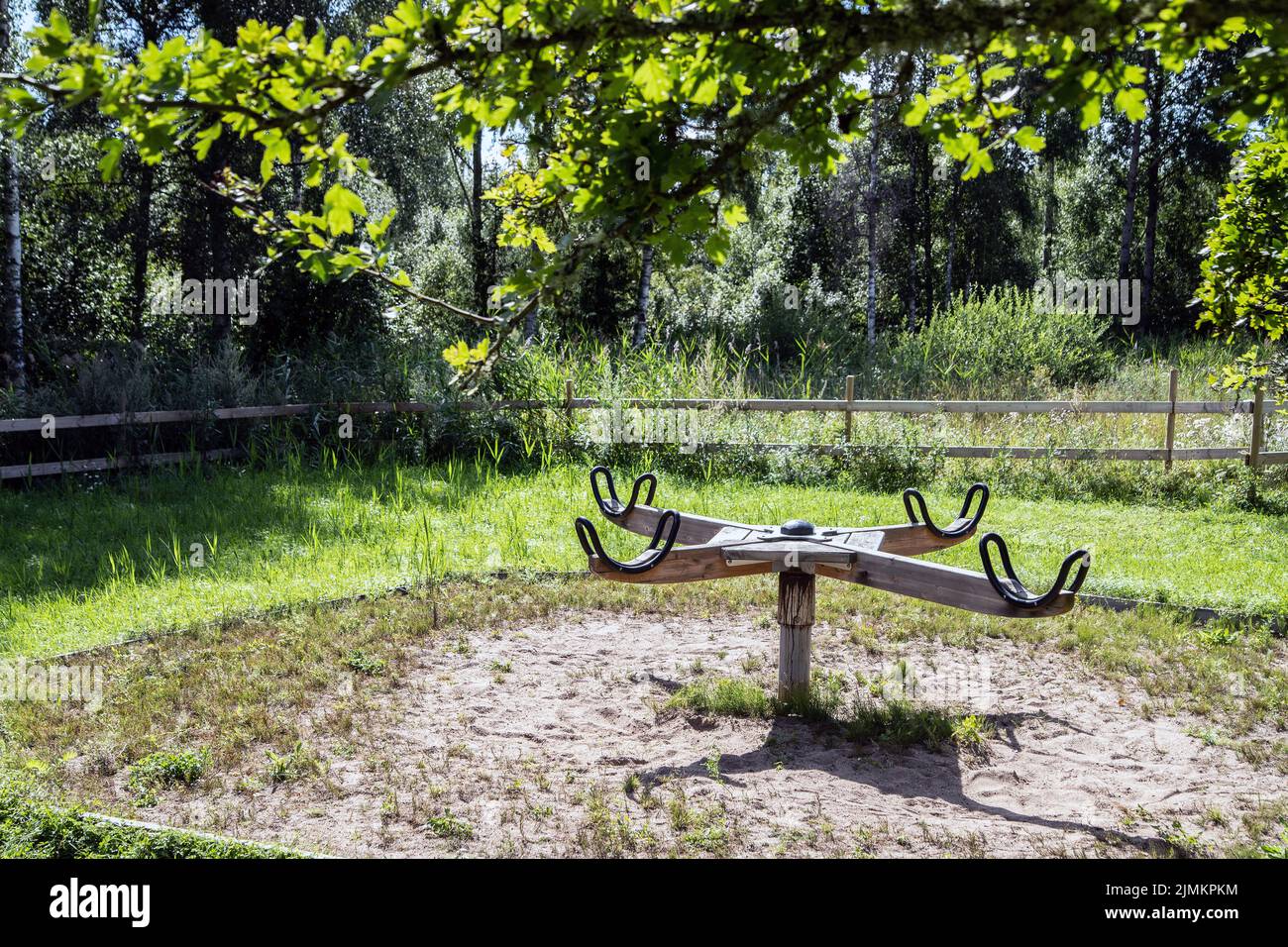 Hölzerne Karussell vor den Wäldern mit etwas überwuchertem Gras an einem sonnigen Sommertag, Foto: Bo Arrhed Stockfoto