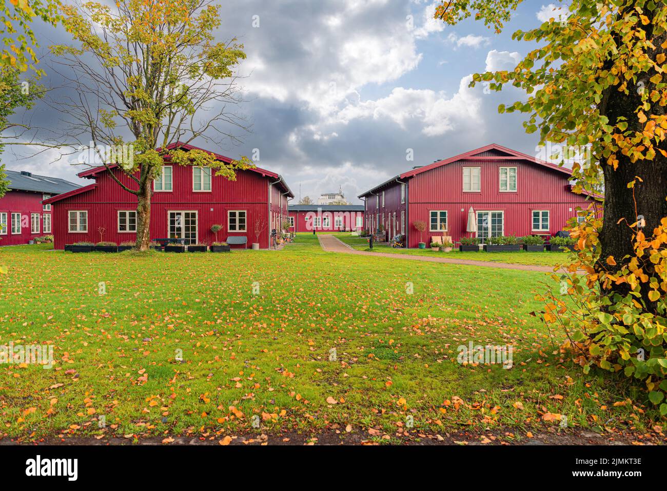 Mehrere identische rote Holzhäuser stehen auf einem Feld mit grünem Gras. Kopenhagen, Dänemark Stockfoto