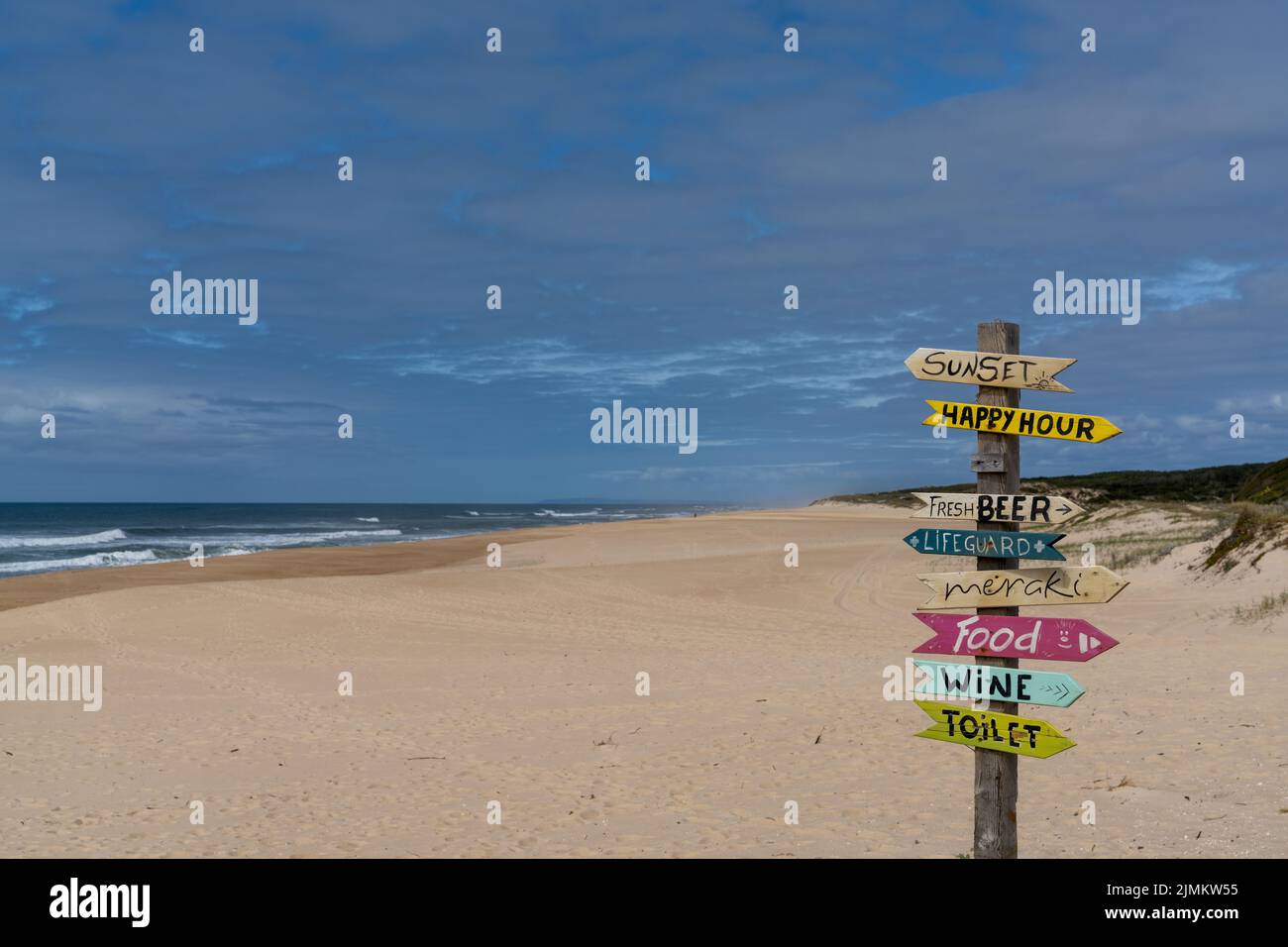 Ein malerischer leerer Strand mit bunten und humorvollen Schildern, die in verschiedene Richtungen zeigen Stockfoto
