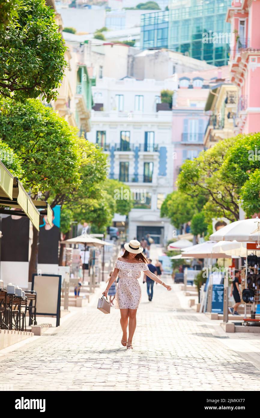 Ein helles, schönes Mädchen in einem hellen Kleid und Hut geht bei sonnigem Wetter im Sommer durch die Straßen von Monaco, ein Wohngebiet Stockfoto