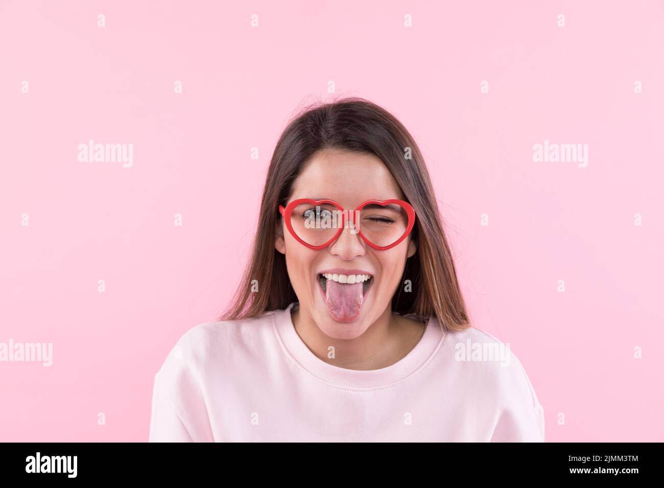 Junge glückliche Frau mit einer Brille, die Zunge zeigt Stockfoto