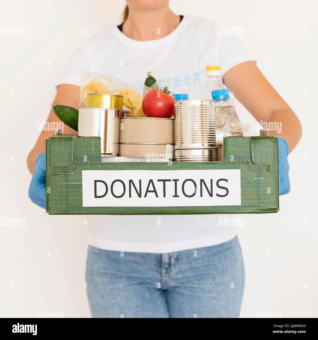 Weibliche Freiwillige mit Handschuhen, die die Schachtel mit Lebensmittelspenden halten Stockfoto