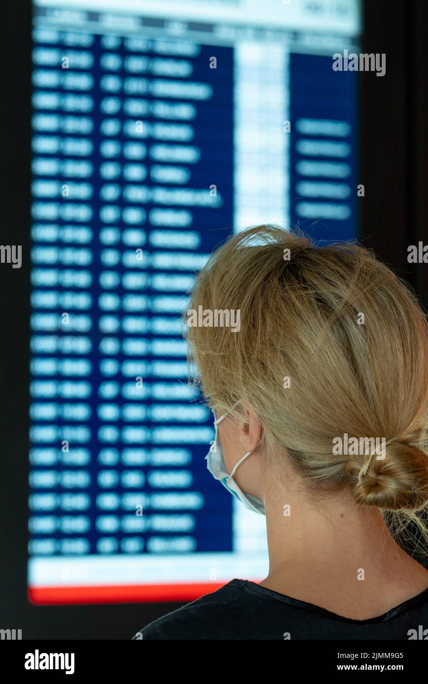 Frau, die auf dem Display mit Informationen zu einem Flug in einem Flughafen aufsieht Stockfoto