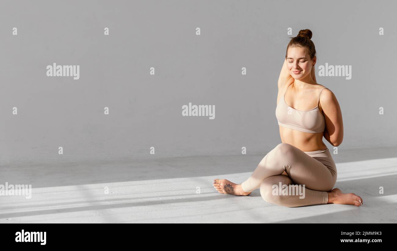 Frau mit voller Schussaufnahme, die sich innen streckt Stockfoto