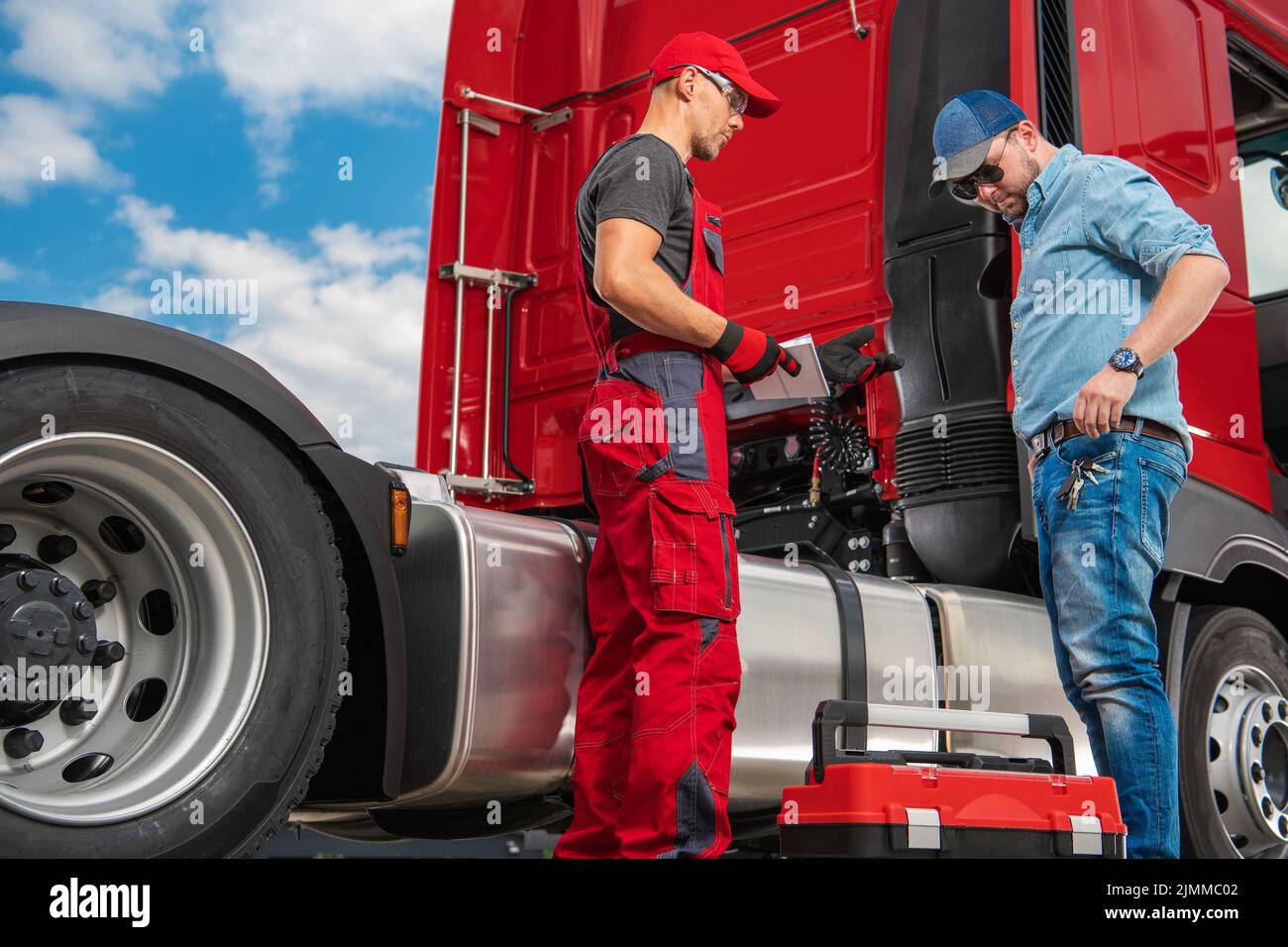 Kaukasischer Semi-Truck-Techniker informiert den traurige Fahrer über die Ergebnisse der ersten Fahrzeugprüfung, um einen weiteren Plan zur Behebung des Devec zu vereinbaren Stockfoto