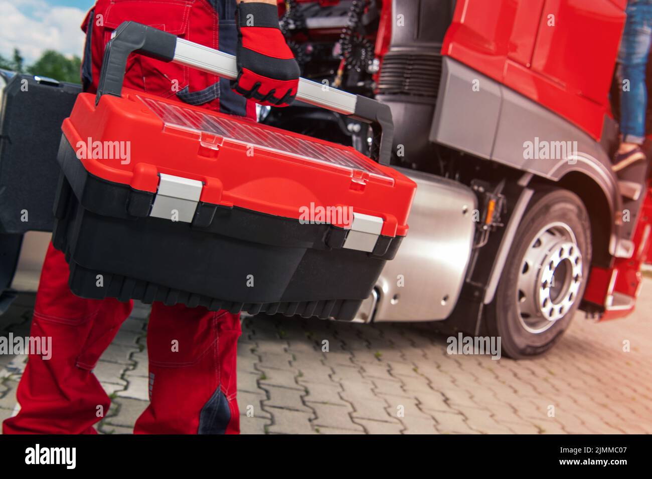 Heavy Duty Fahrzeugtechniker mit großem Werkzeugkasten in der Hand auf dem Weg zum Red Semi Truck, um eine Reparatur zu machen. Nahaufnahme Horizontales Foto. Stockfoto