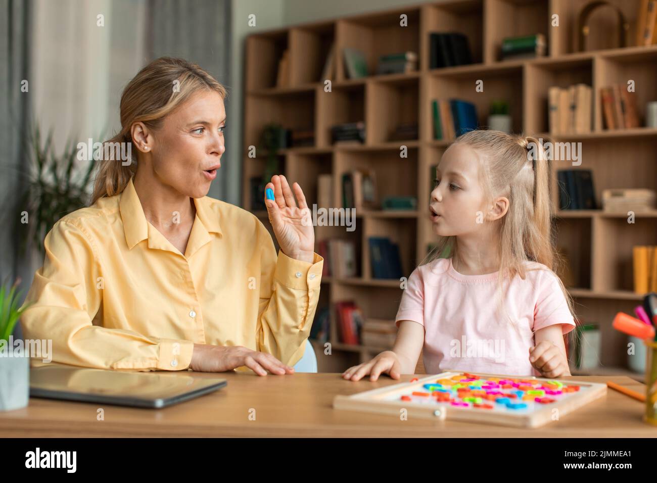 Fürsorgliche Mutter unterrichtet kleine Vorschulkinder Tochter spricht Wörter und Buchstaben richtig aus Stockfoto