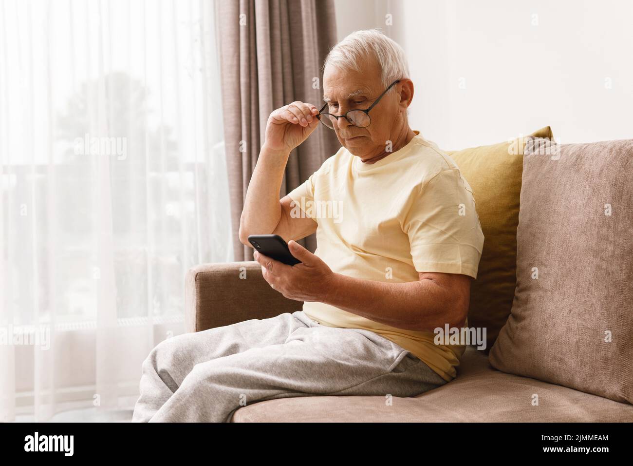Ein älterer Mann mit Brille verwendet ein Smartphone Stockfoto