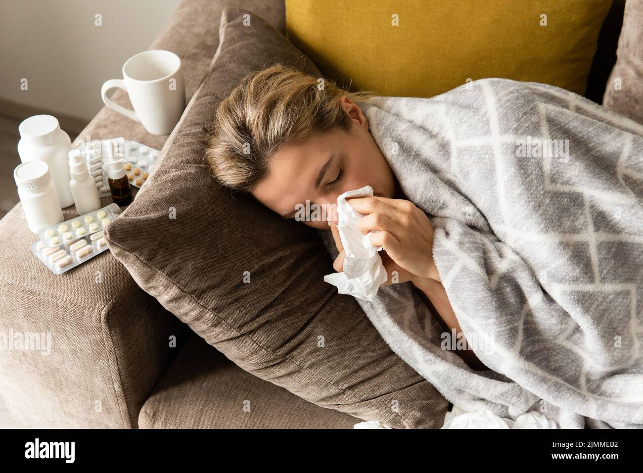 Frau mit einem laufenden Nasensymptom, die zu Hause unter der Decke liegt Stockfoto