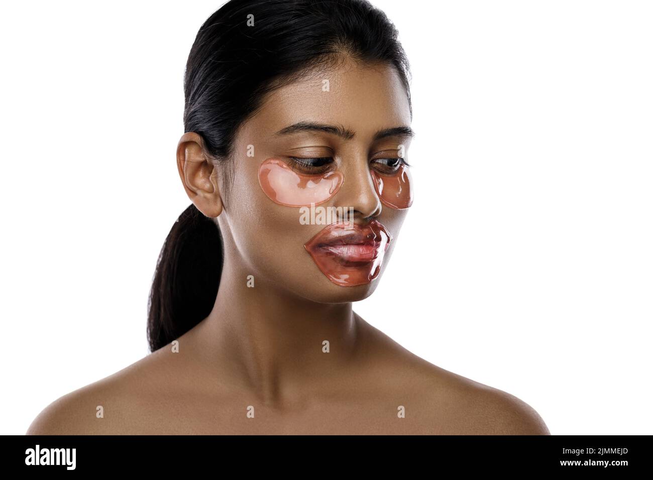 Schöne indische Frau mit feuchtigkeitsspendenden Augenflecken und Lippenmaske auf ihrem Gesicht Stockfoto