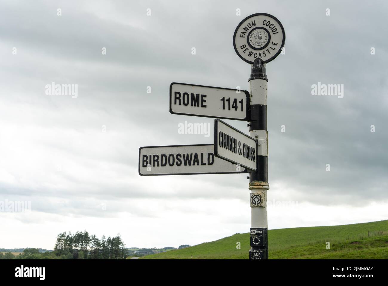 Wegweiser in Bewcastle Castle, Cumbria, Großbritannien, erbaut aus Stein der ehemaligen römischen Festung, zeigt die Entfernung nach Rom und anderen Orten. Stockfoto