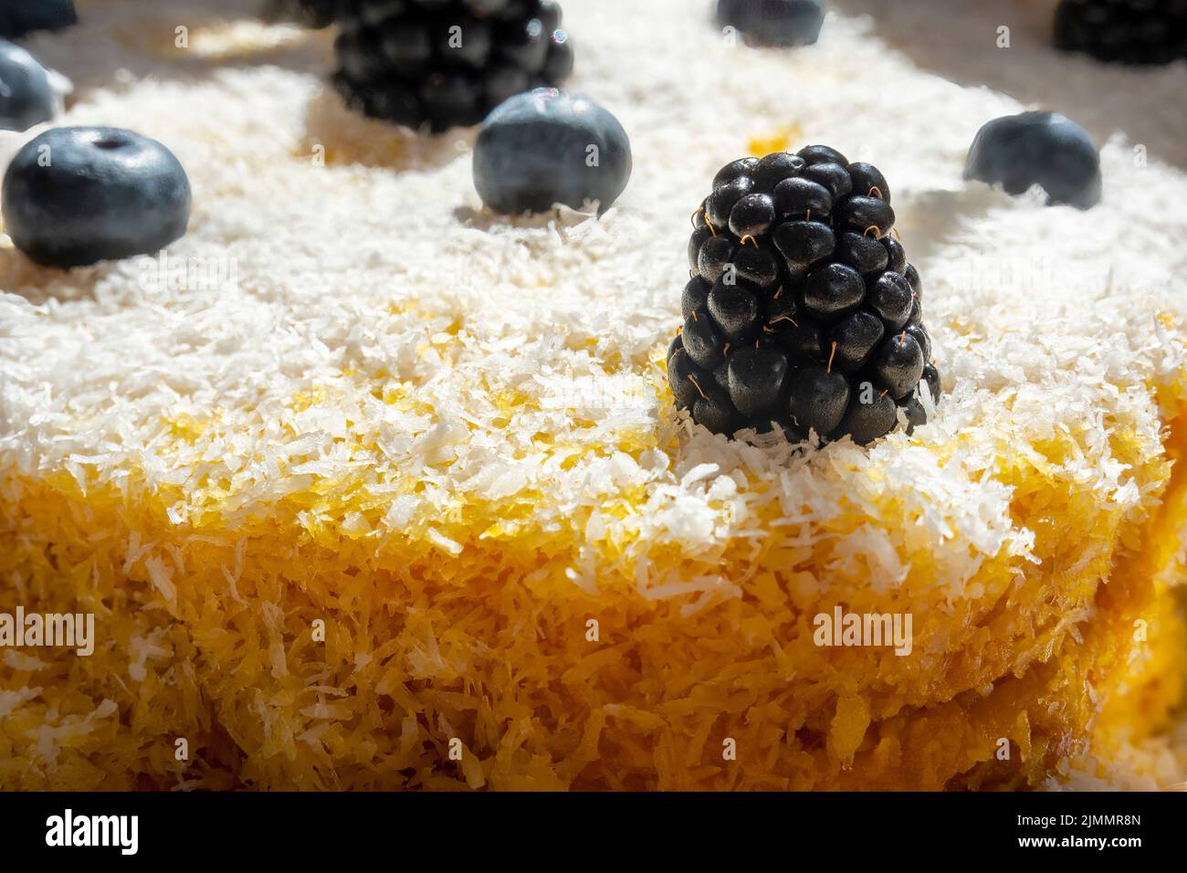 Nahaufnahme eines köstlichen hausgemachten Karottenkuchens mit geriebener Kokosnuss, Brombeeren und Blaubeeren, geeignet für Vegetarier und Veganer. Stockfoto