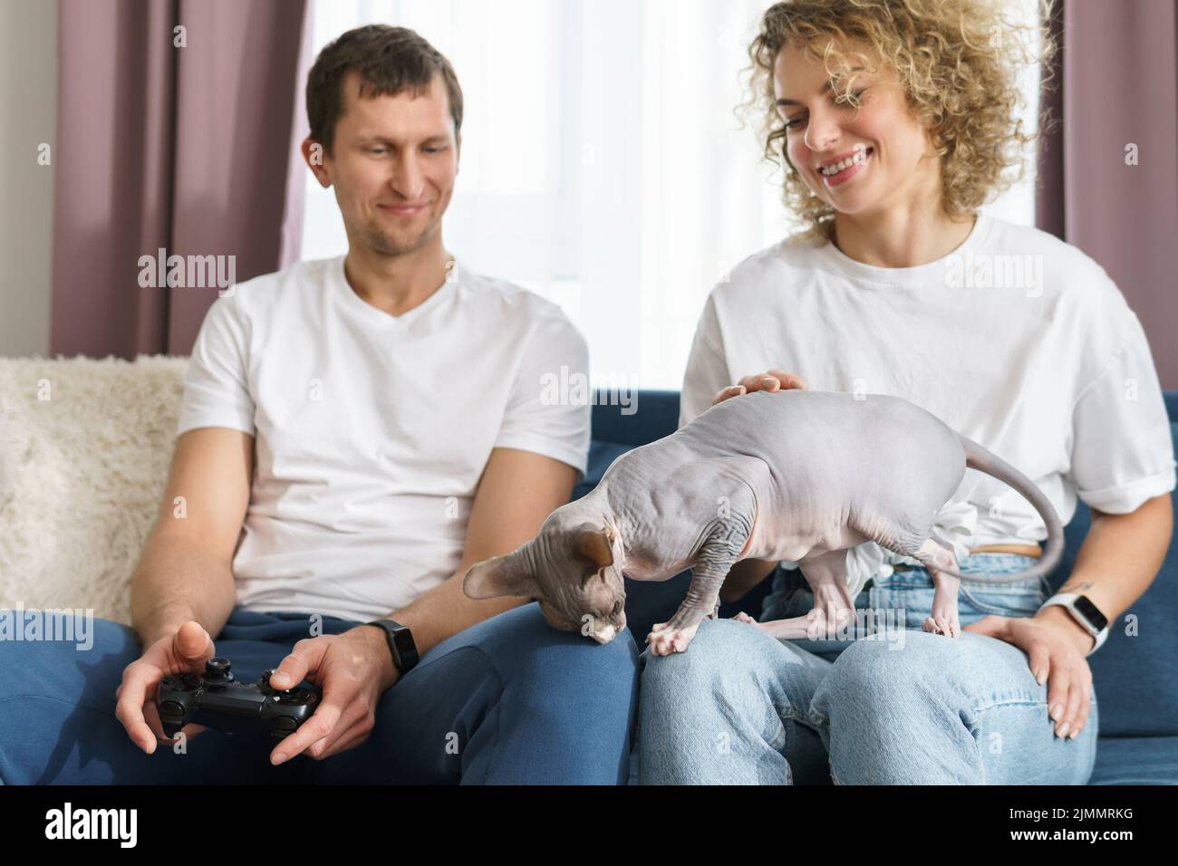 Das Paar und ihre Sphynx-Katze entspannen sich zu Hause Stockfoto