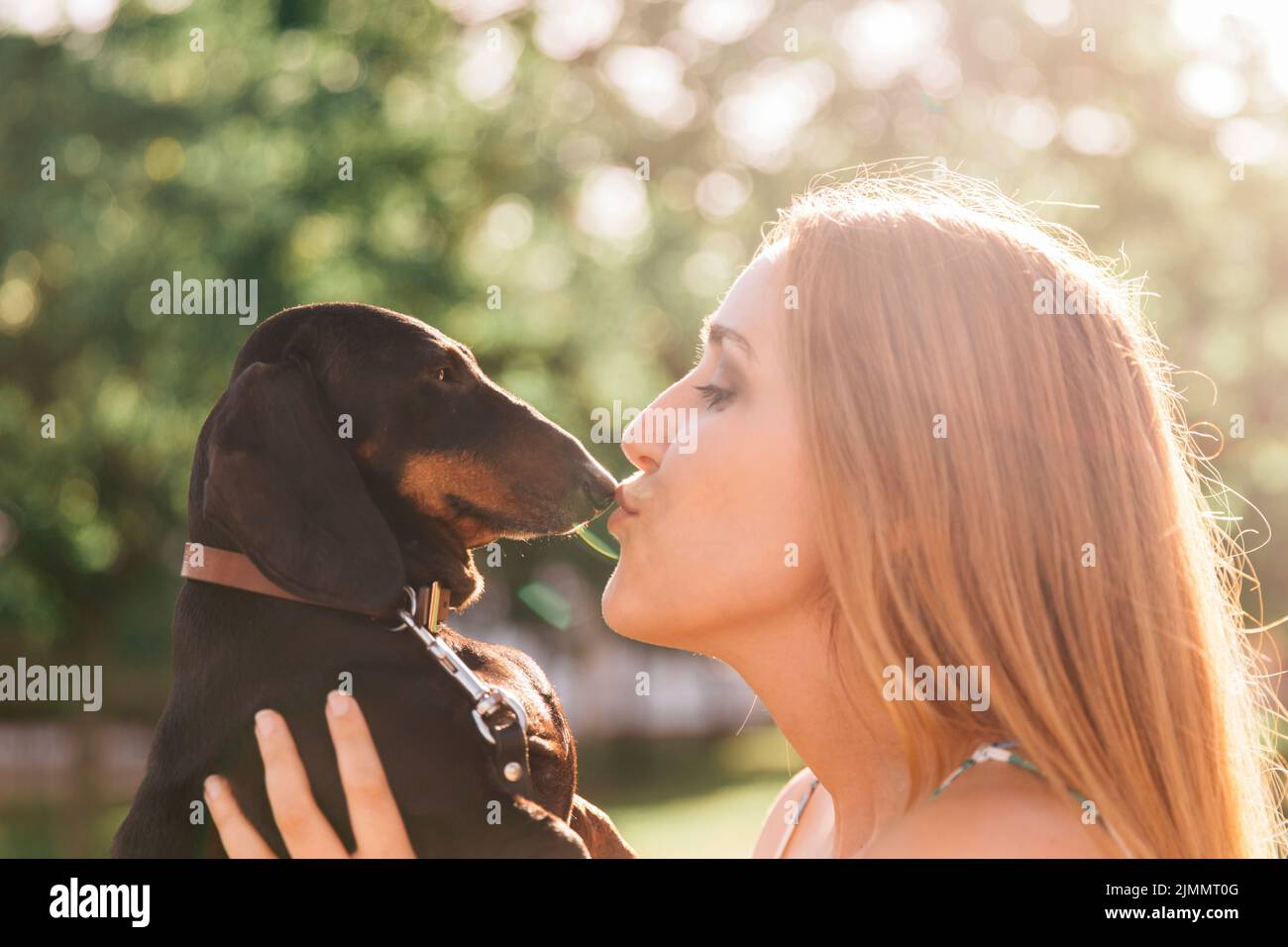 Seitenansicht schöne junge Frau küssen ihren Hund Stockfoto