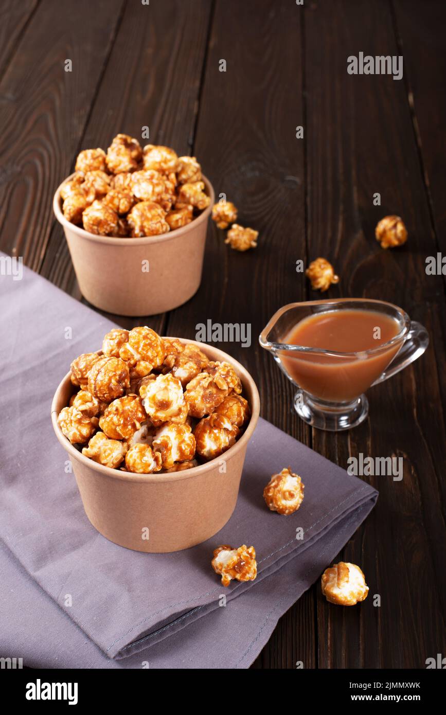 Karamellisiertes Popcorn in Papiereimer auf Holztisch Stockfoto