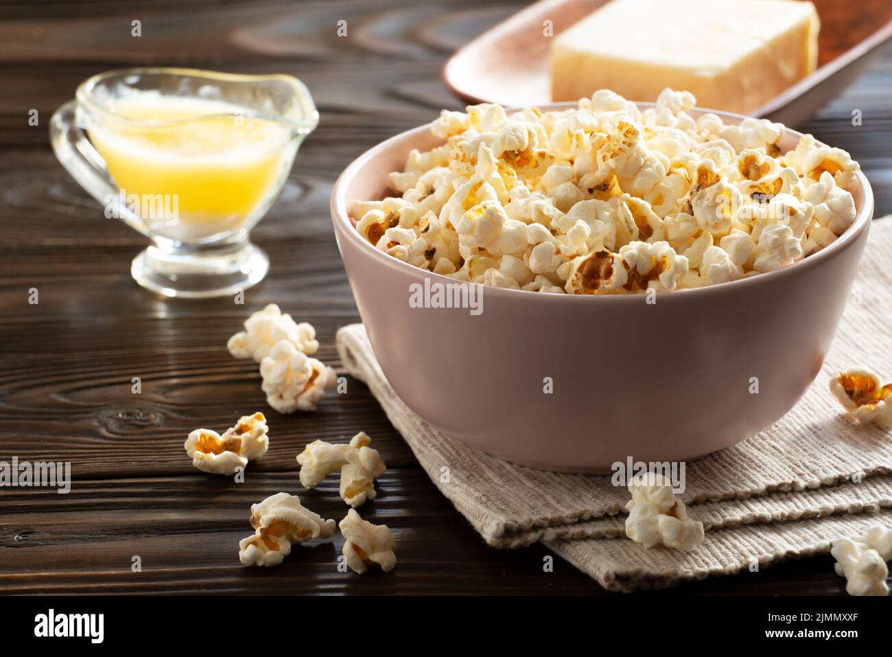 Popcornschüssel und geschmolzene Butter auf dem Küchentisch Stockfoto