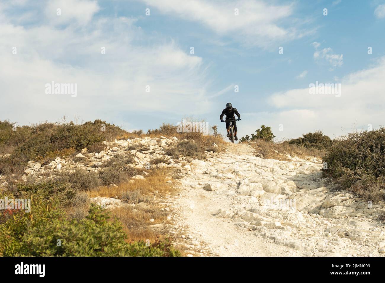 Fahrer voll ausgestattet mit Schutzausrüstung während bergab Fahrt auf seinem Fahrrad Stockfoto