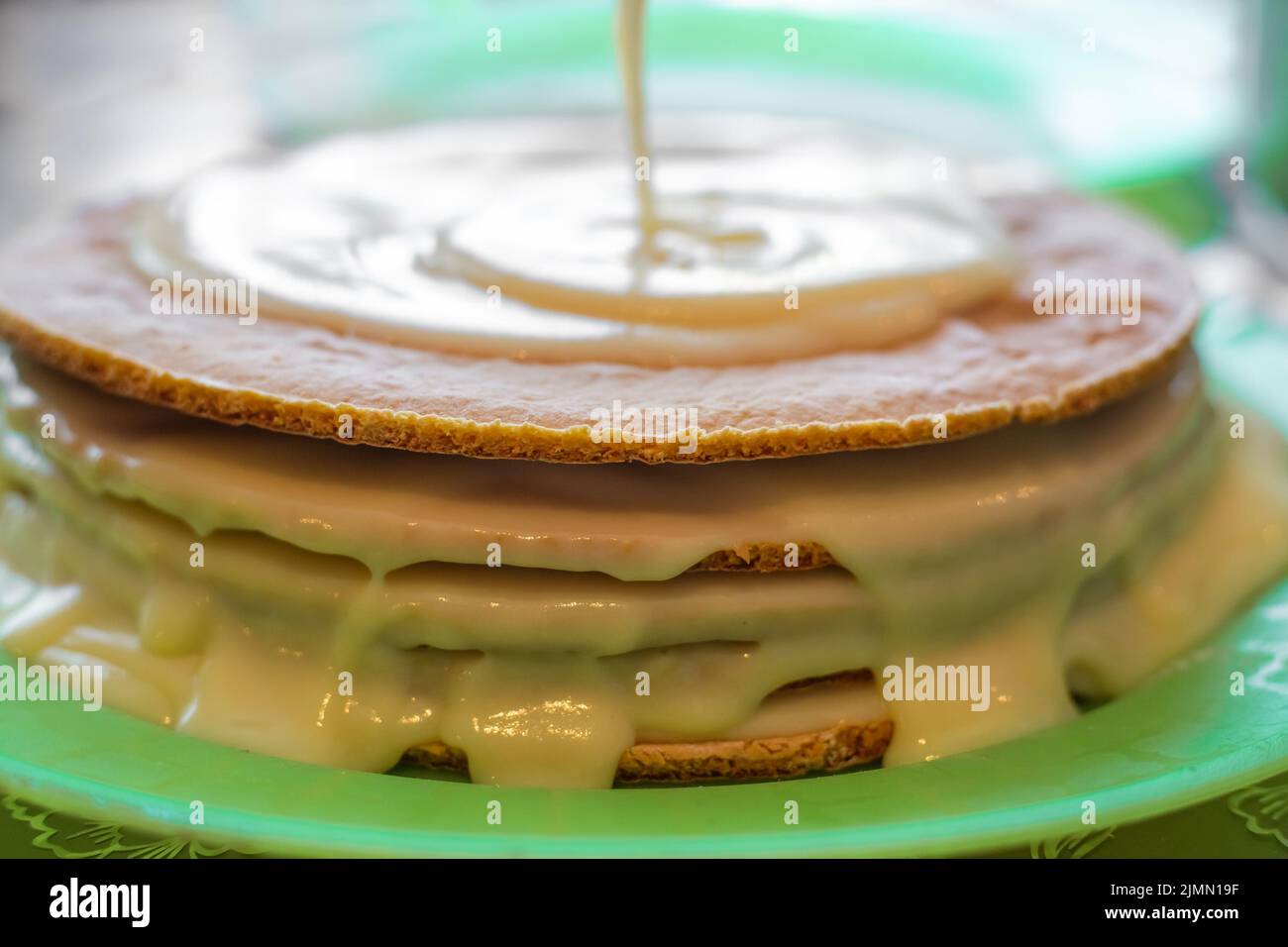 Kochen hausgemachten Kuchen. Pudding wird auf die gebackenen Kuchen Schichten gegossen. Stockfoto