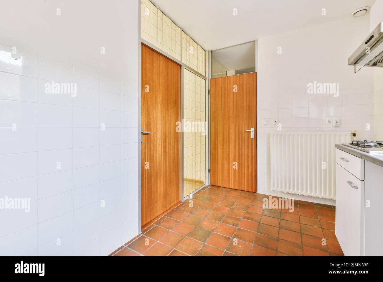 Gut organisierte kleine Wohnküche mit Waschbecken unter dem Fenster Und helle Möbel mit Herd und Kühlschrank in städtischen Wohnung Stockfoto