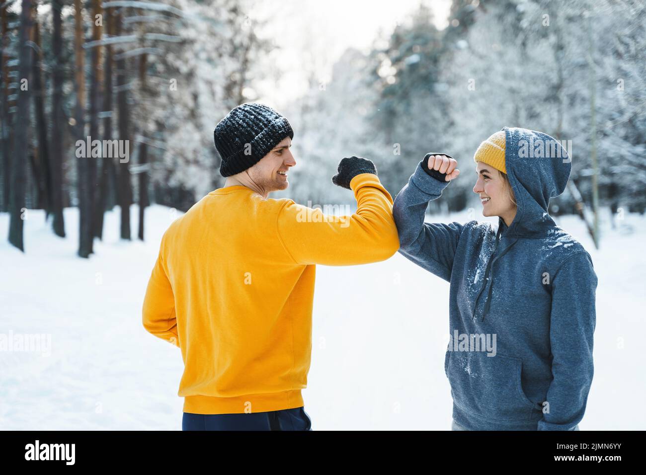 Zwei Jogger begrüßen sich beim Wintertraining mit einer Ellbogenbewegung Stockfoto