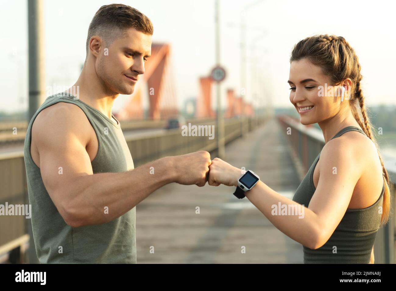 Das athletische Paar macht beim Fitnesstraining auf der Stadtstraße eine Fauststoß-Geste Stockfoto