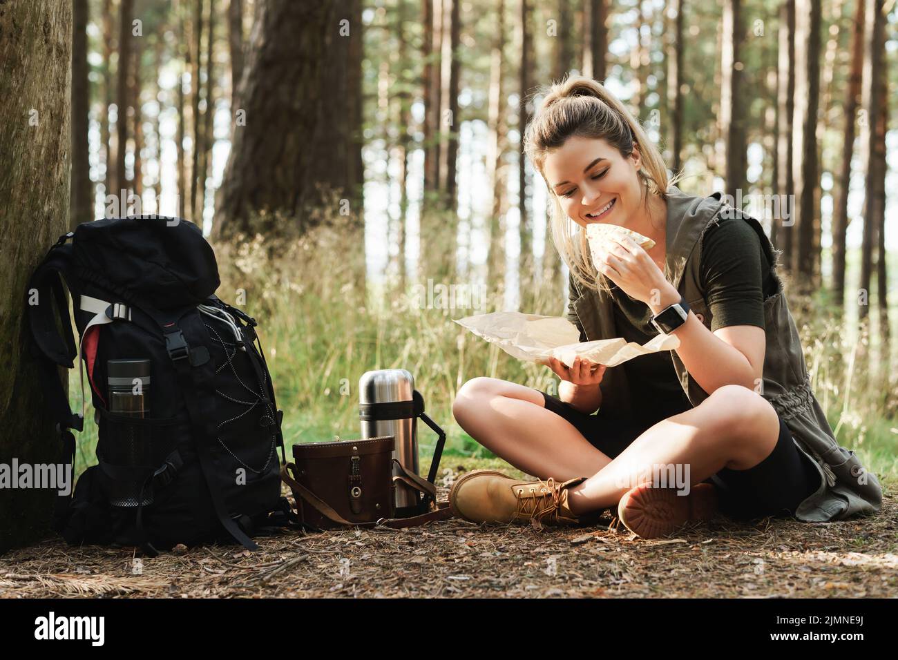Weibliche Wanderer während des kleinen Halt essen Sandwich in grünem Wald Stockfoto