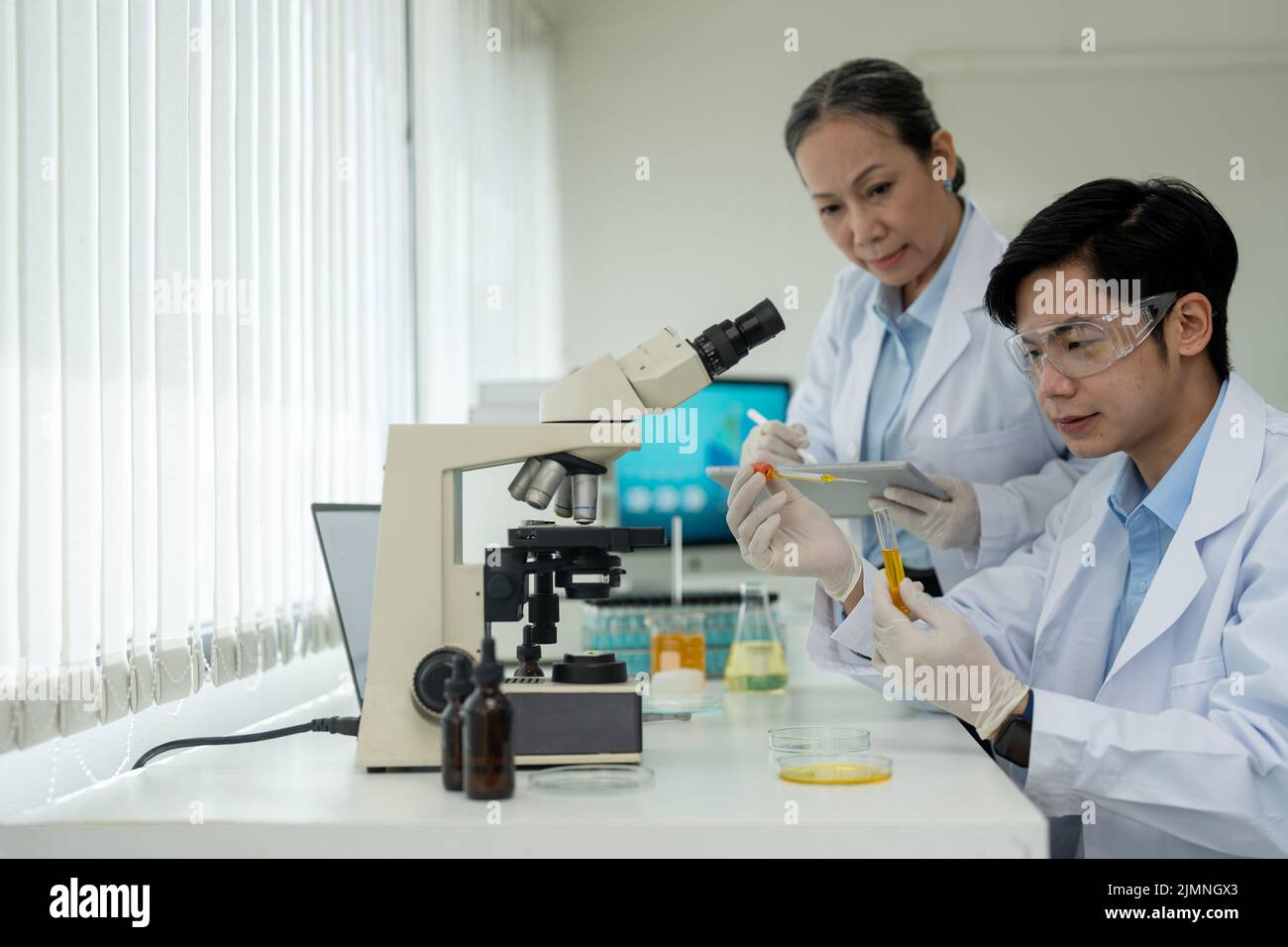 Biochemische Forscher arbeiten mit Mikroskop für die Impfstoffentwicklung in der pharmazeutischen Forschung labolatory. Stockfoto
