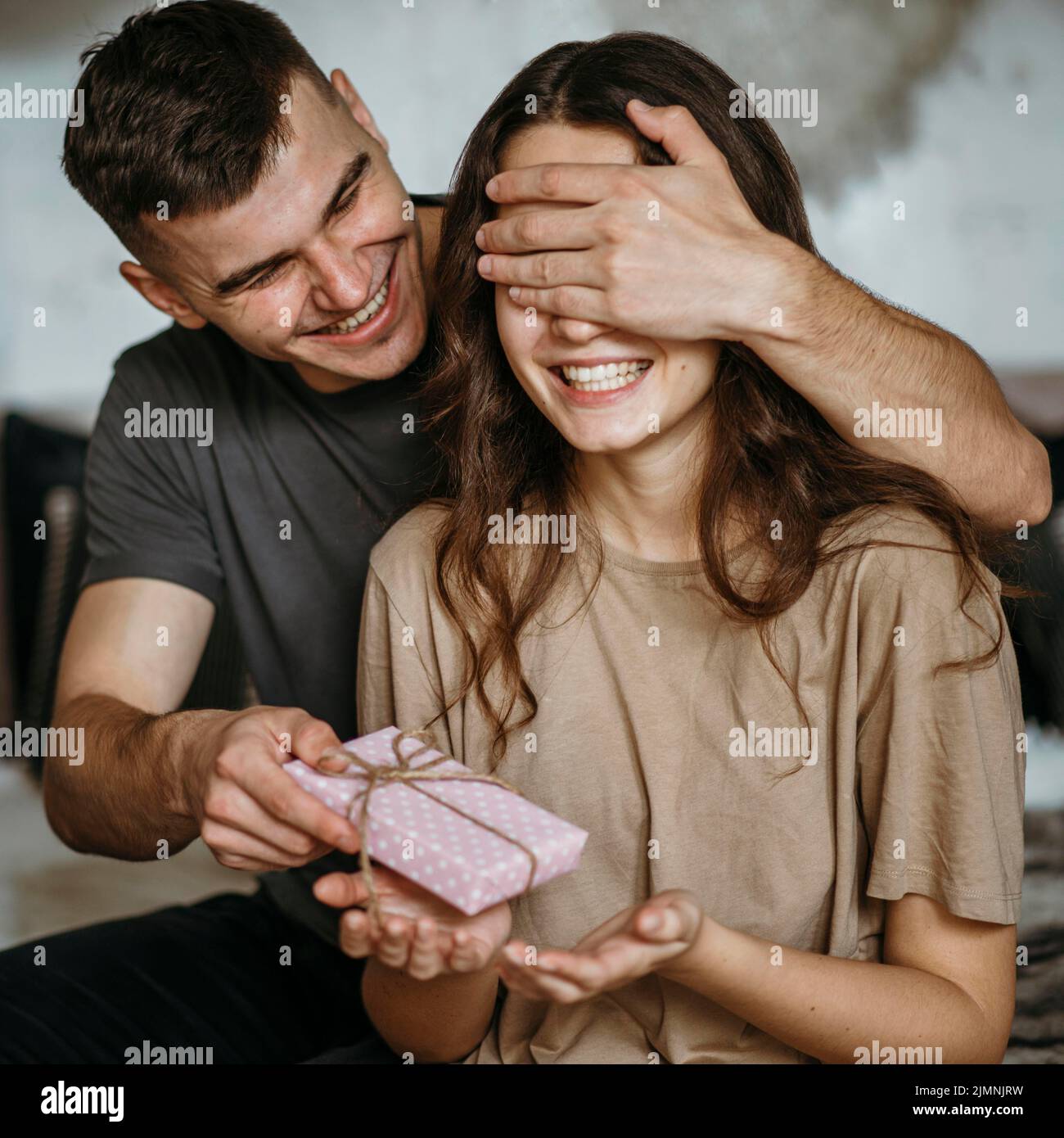 Junger Mann überraschende Freundin mit Geschenk Stockfoto