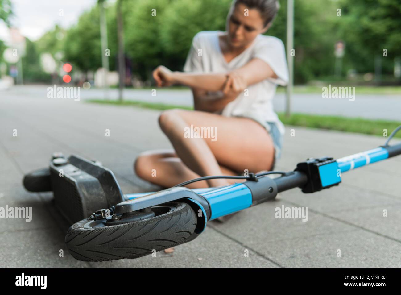 Junge Frau, die nach einem E-Scooter-Fahrunfall unter Ellenbogenschmerzen leidet Stockfoto