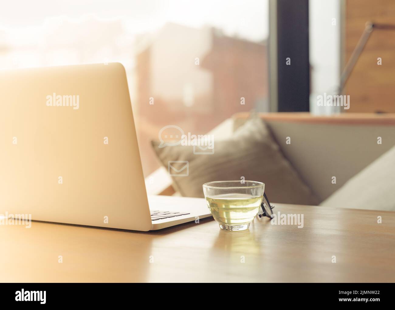 Freiberuflicher Schreibtisch mit offenem Laptop, einer Tasse grünem Tee und Gläsern auf dem Tisch. Café oder Coworking Space. Konzept der digitalen Nomaden, Home Stockfoto
