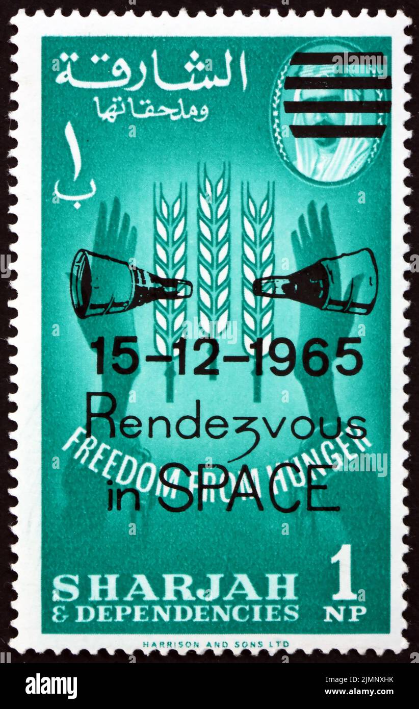 SHARJAH - UM 1963: Eine in Sharjah VAE gedruckte Marke zeigt Weizenemblem und Hände mit gebrochenen Ketten, Hungerfreiheit, Rendezvous im Weltraum, circa Stockfoto