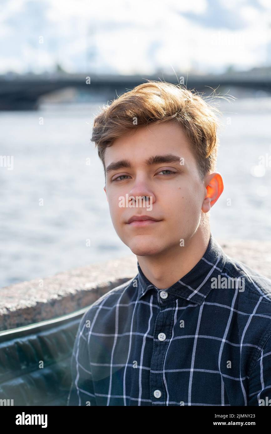 Porträt von jungen Kerl, brünett mit dunklen Haaren, kaukasisch. Nahaufnahme eines Mannes, Jungen, Mannes, der die Kamera anschaut. Outdoor in der Stadt durch w Stockfoto