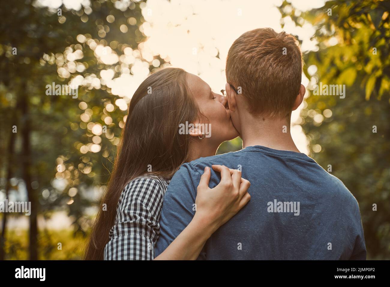 Mädchen küssen Jungen in Wange im Park, Konzept der Teenager-Liebe Stockfoto