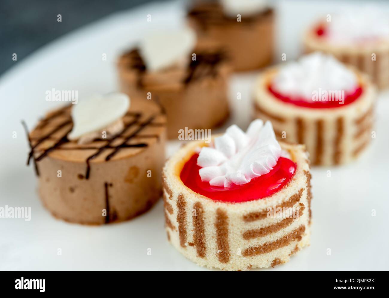 Kleine Kuchen mit verschiedenen Füllungen auf weißen Teller Stockfoto