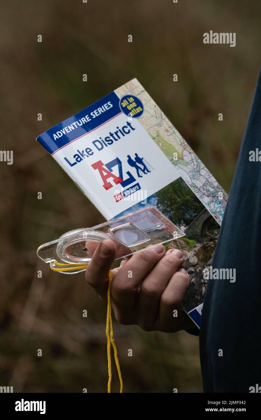 A-Z Karte und Kompass in Menschenhand bei der Erkundung des Lake District Stockfoto