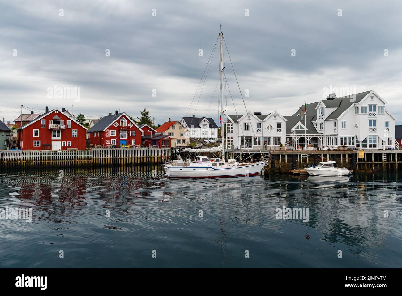Norwegische Seestücke, Stadtbild der Stadt Henningsvaer, ein kleines Boot bewegt sich zwischen Halbinseln, Segelboot, felsige Küste mit Drama Stockfoto