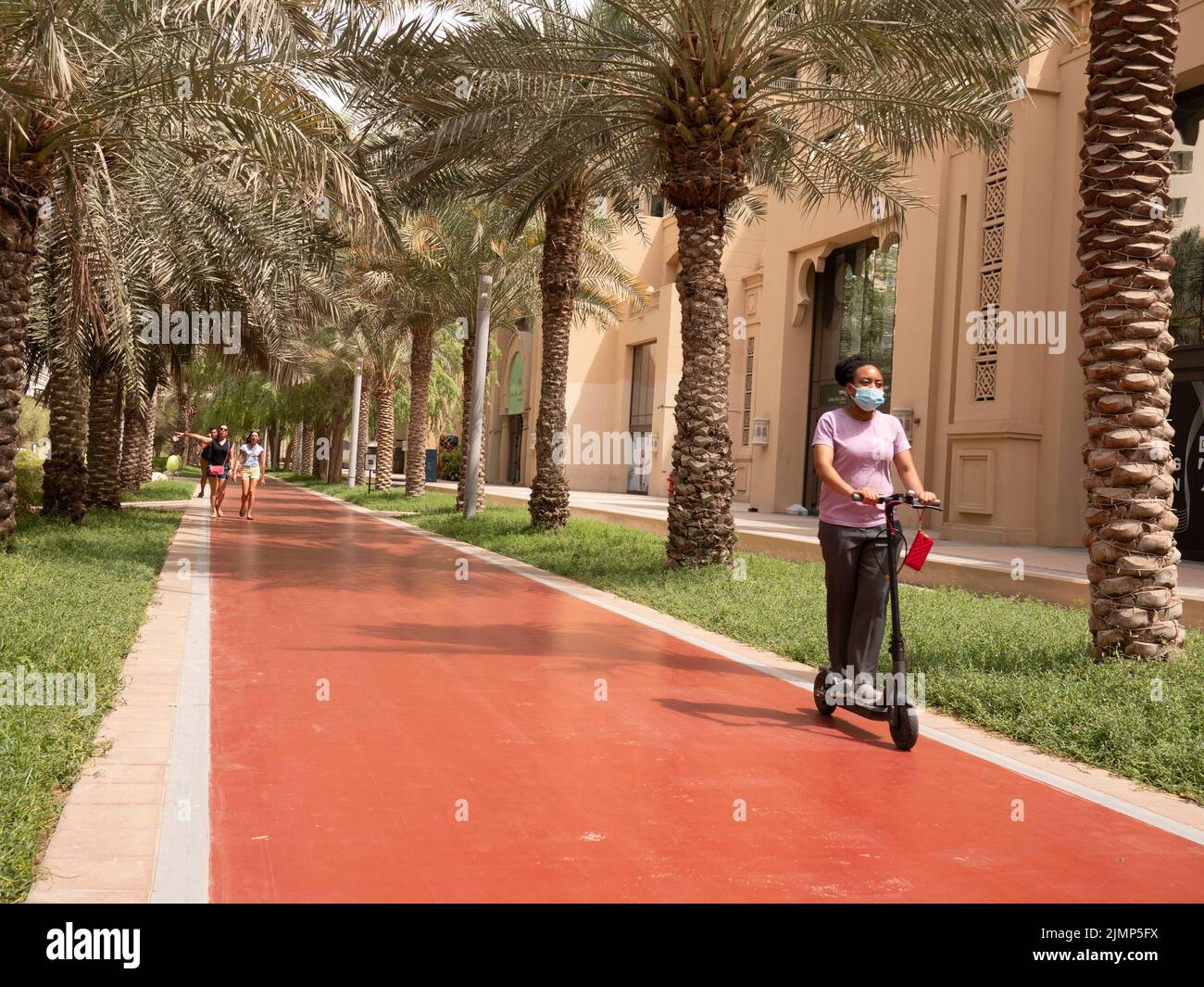 Al Ittihad Park Running Walking Track, Dubai VAE, Vereinigte Arabische Emirate, mit Elektroroller Fahrer tragen PPE, covid Maske, Stockfoto