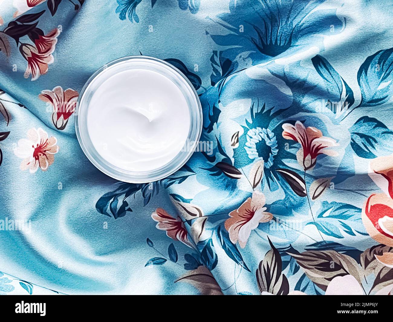 Hautpflege Kosmetik, Gesichtscreme Feuchtigkeitscreme Glas auf blauem floralem Hintergrund, Beauty-Produkt Flatlay Stockfoto
