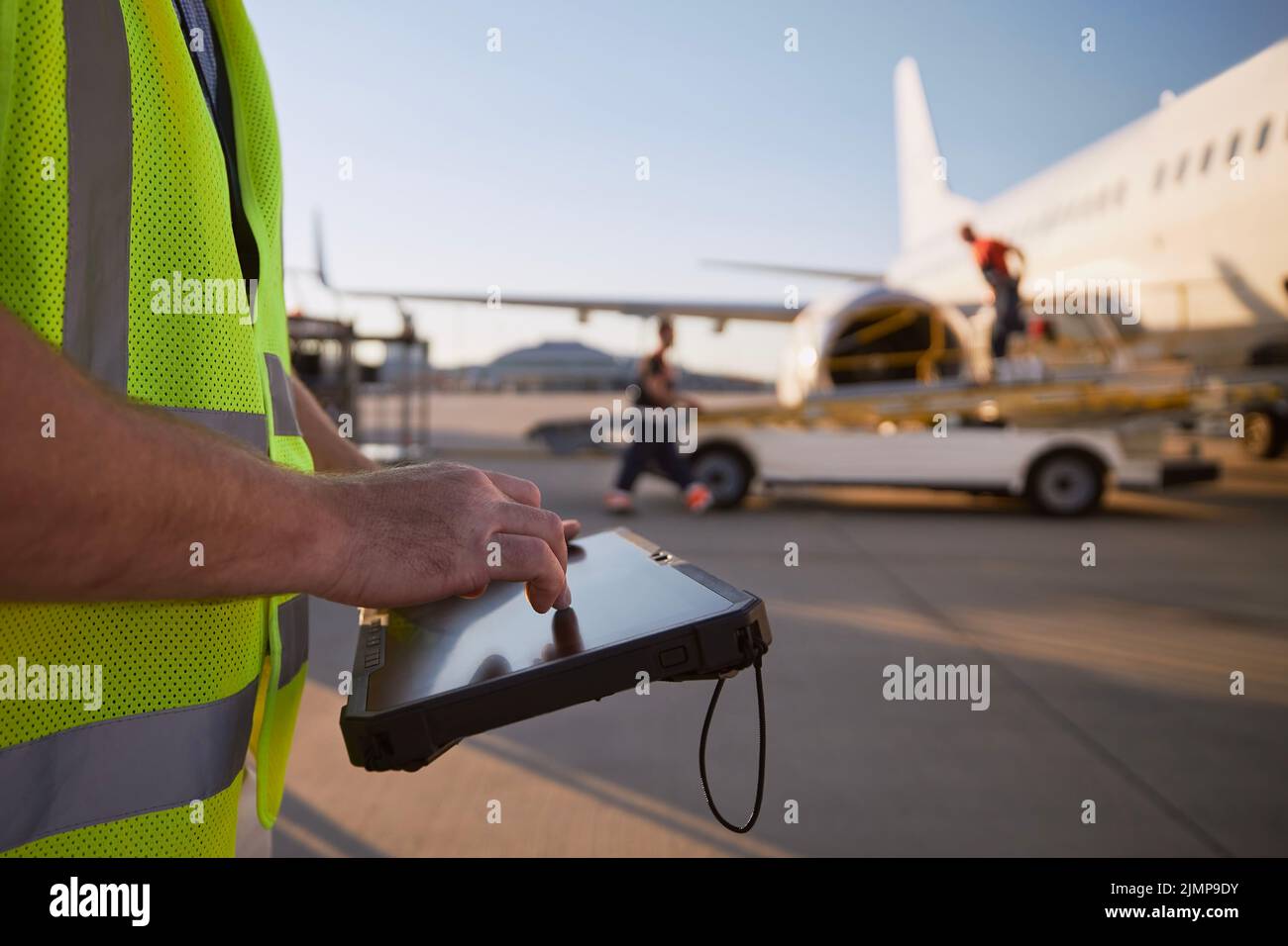 Mitglied der Bodenbesatzung, die das Flugzeug vor dem Flug vorbereitet. Arbeiter, die am Flughafen ein Tablet gegen das Flugzeug benutzen. Stockfoto