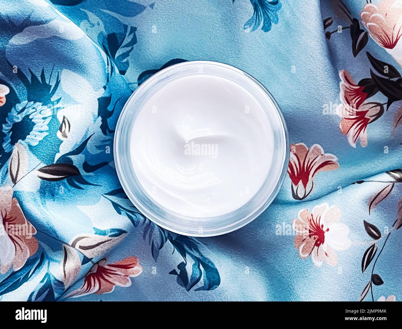 Hautpflege Kosmetik, Gesichtscreme Feuchtigkeitscreme Glas auf blauem floralem Hintergrund, Beauty-Produkt Flatlay Stockfoto