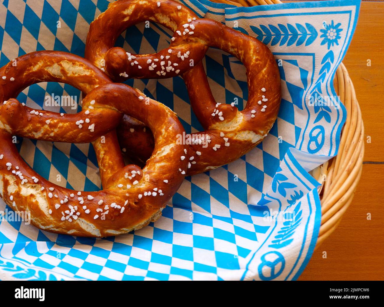 Köstliche bayerische Brezeln oder Brezeln mit brauner Salzkruste auf einer traditionellen bayerischen Cocktailserviette im Korb Stockfoto