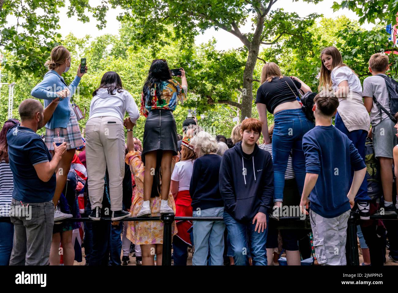 Junge Menschen, die auf der Eisenbahn entlang der Mall stehen, machen Fotos von der Queen's Birthday Parade, Platinum Jubilee Celebrations, London, Großbritannien. Stockfoto