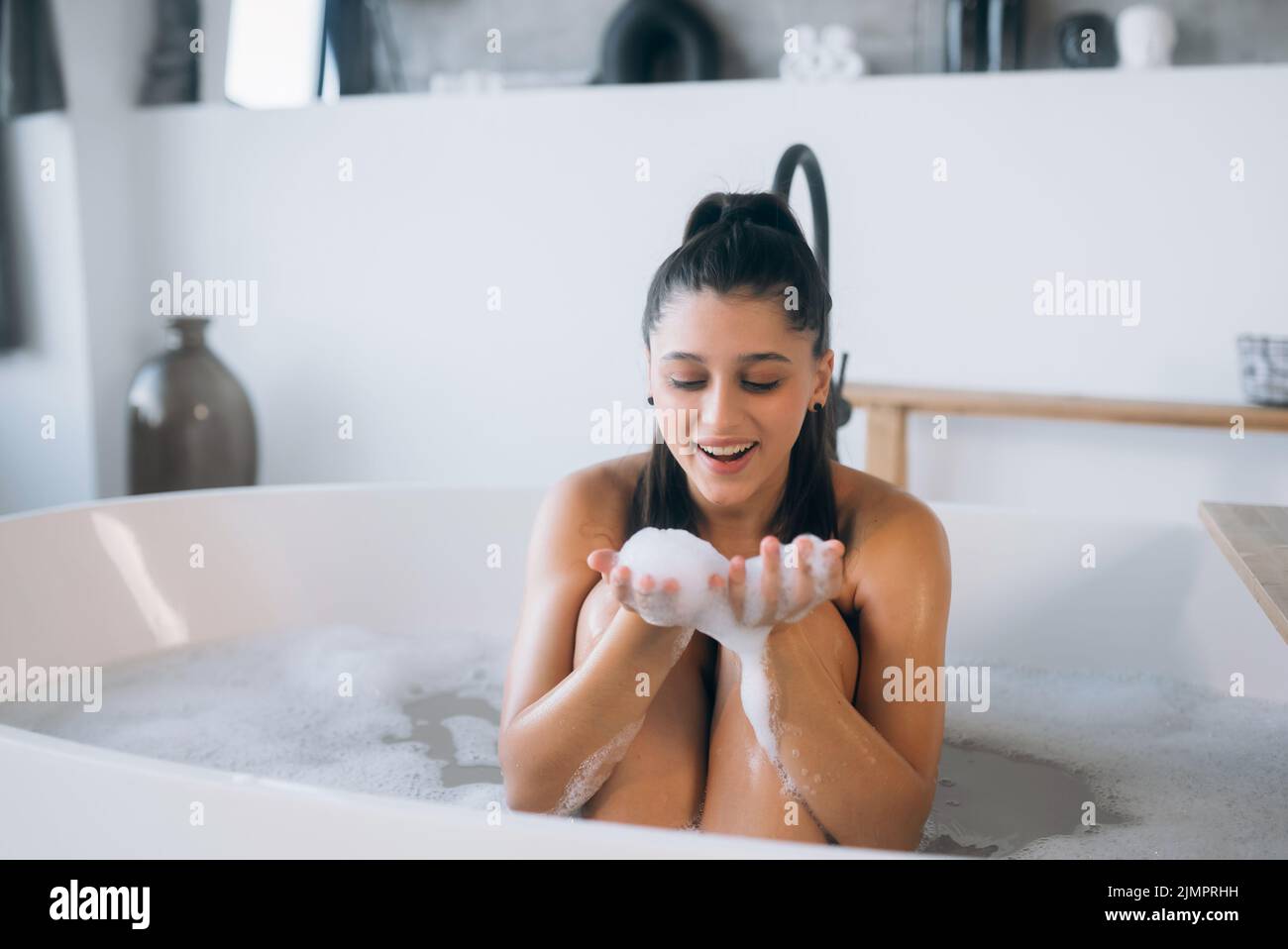 Die junge Frau genießt den Schaum beim Baden Stockfoto