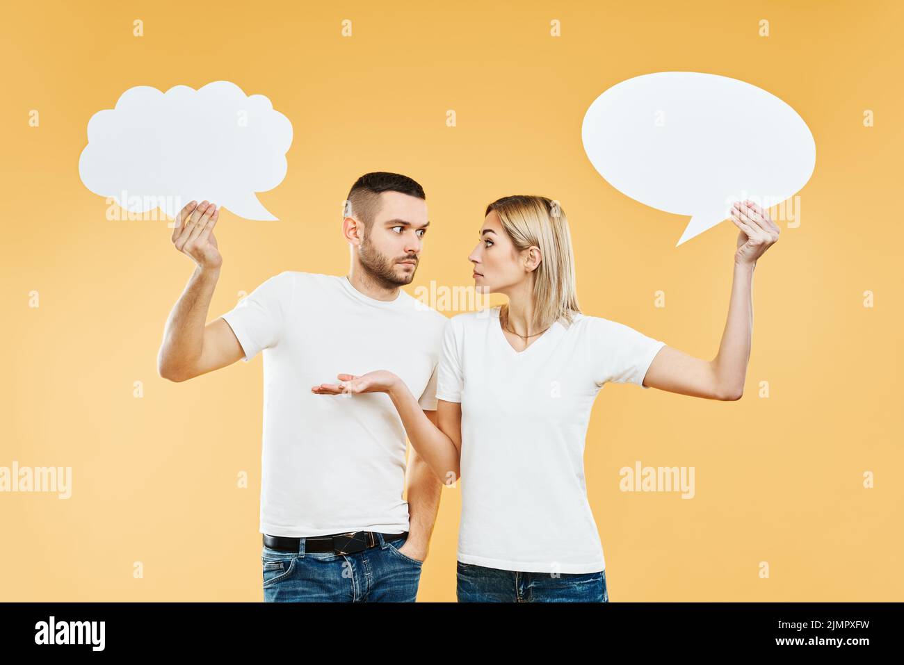 Überrascht Frau und Mann halten Papier Gedanken Blasen über gelben Hintergrund Stockfoto