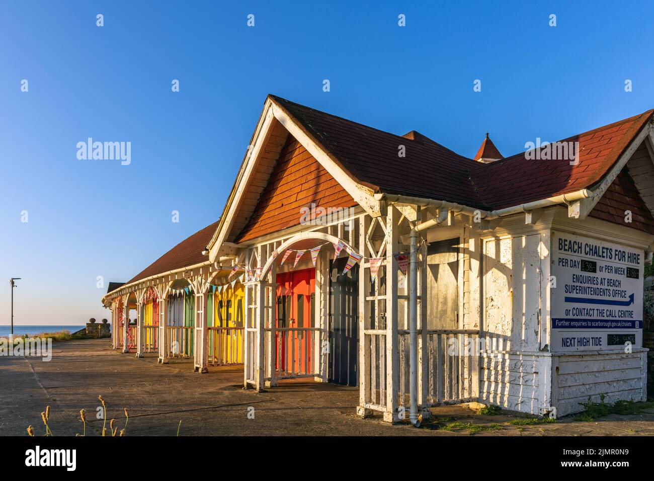 Eine Terrasse mit farbenfrohen, historischen edwardianischen Strandhütten oder Chalets an der South Bay in Scarborough, North Yorkshire, England. Jetzt aufgrund des Landverrutsches verkommen. Stockfoto